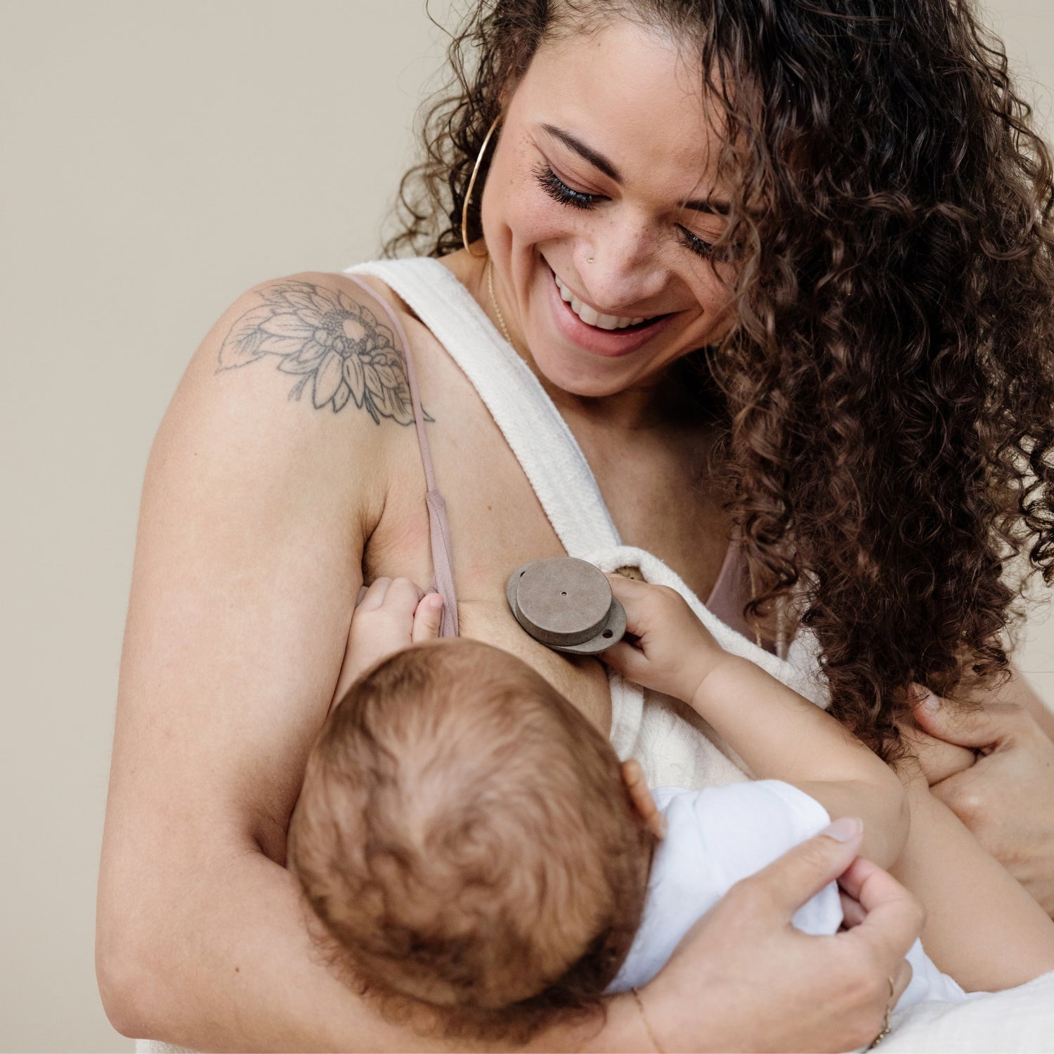 woman breastfeeding a baby holding onto a Soothe Beginnings pacifier